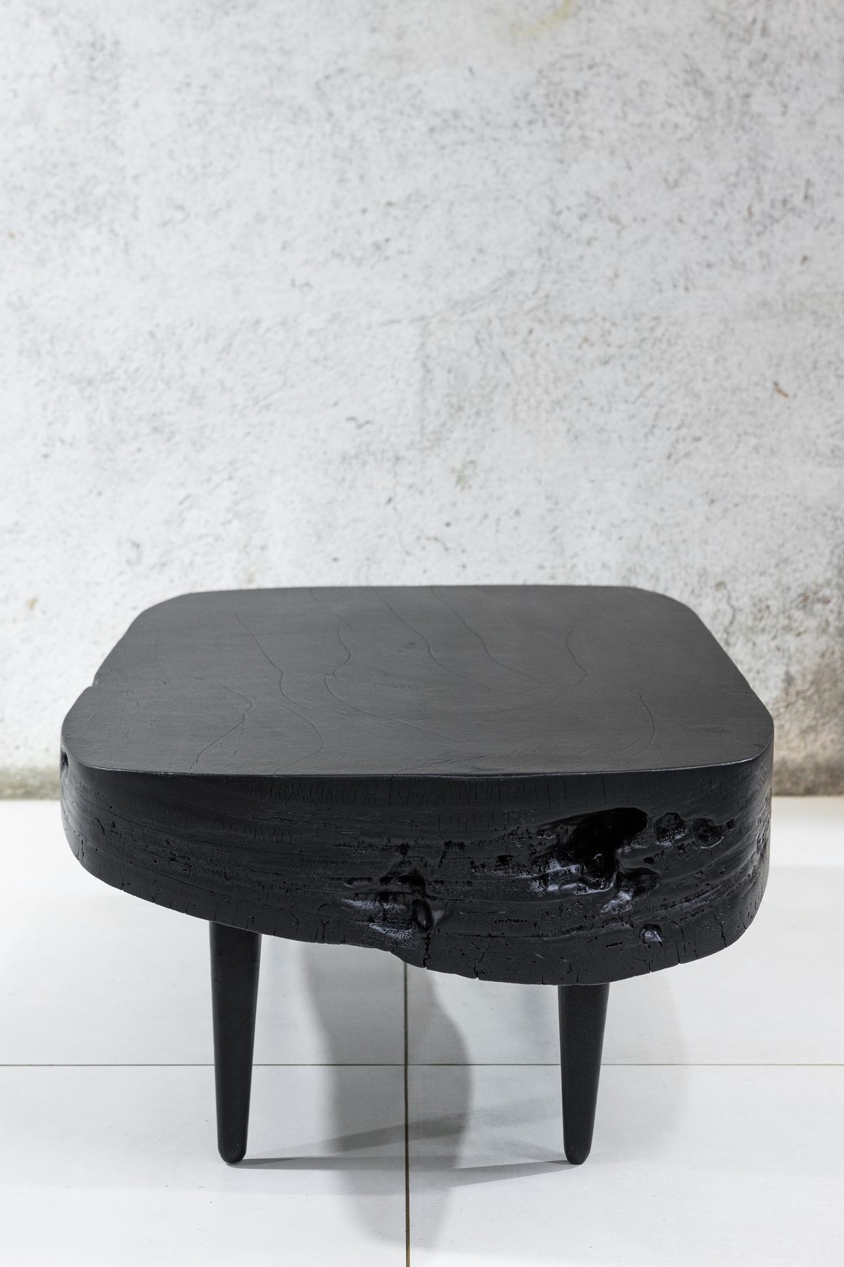 Sabana Brasa from three-quarters, matte black top over a deeply charred live edge