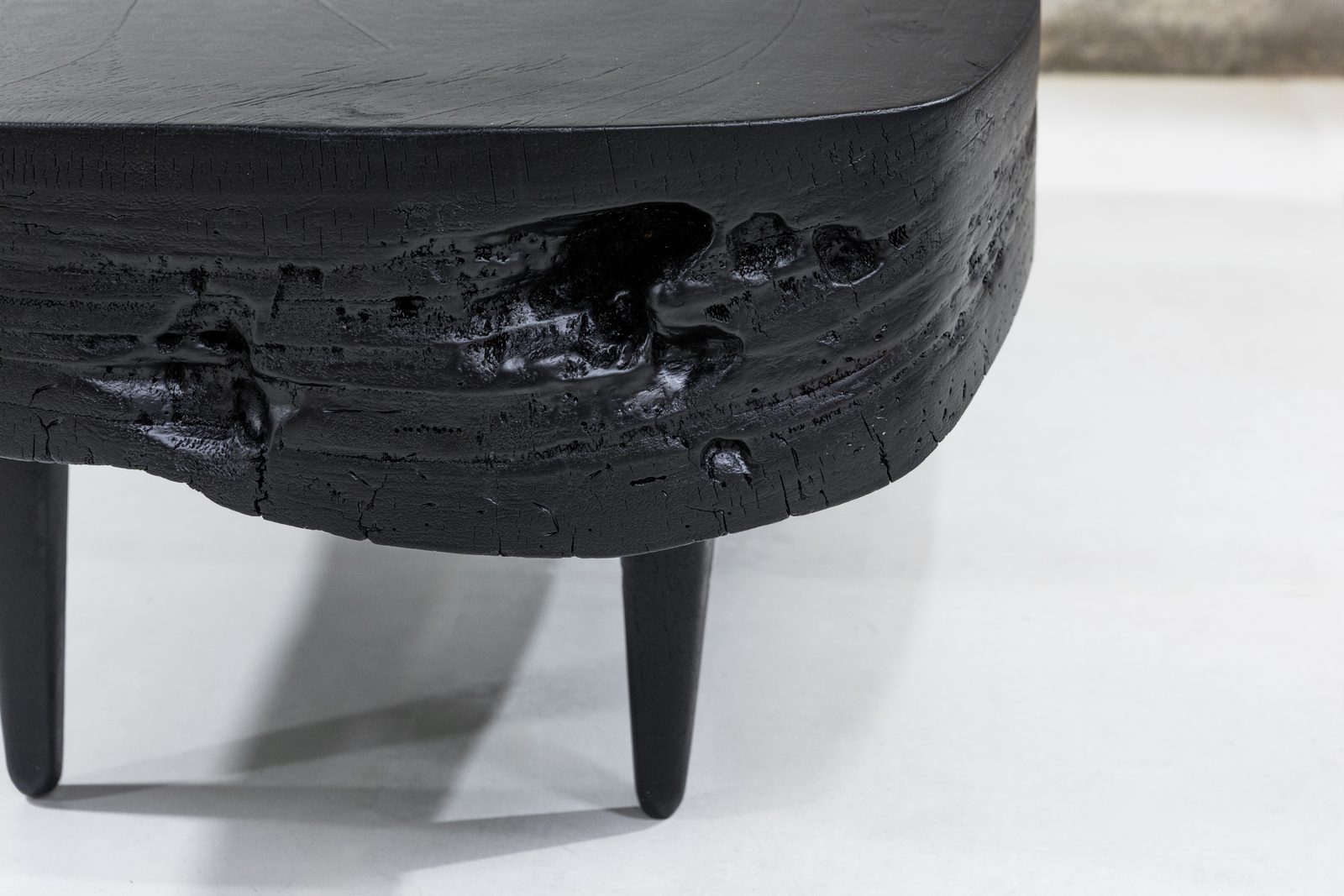 Close detail of the charred live edge on Sabana Brasa — cracked, alligatored black char with a glossy surface