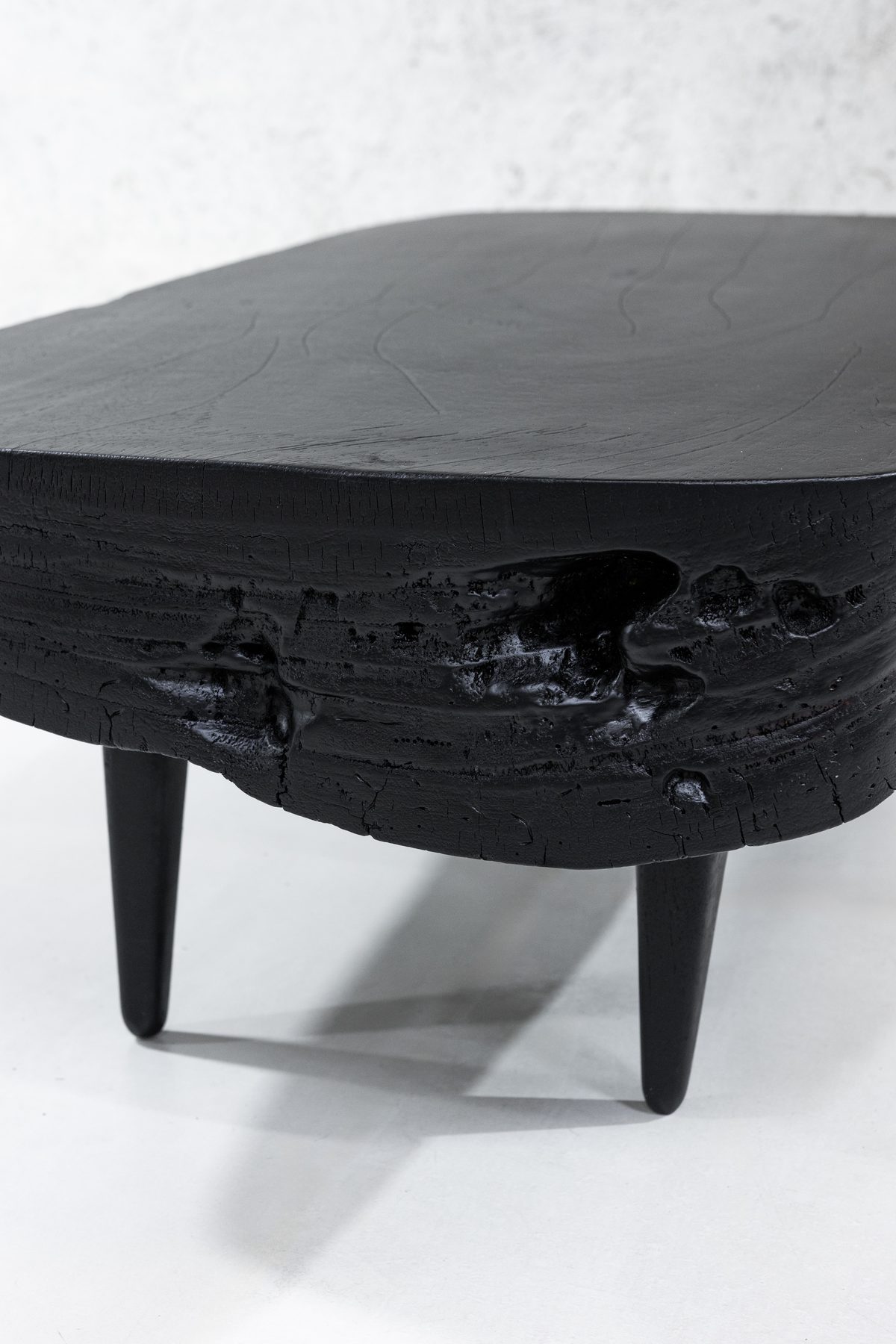Detail of Sabana Brasa — grain still visible under the matte black top, glossy char pooling in the live edge