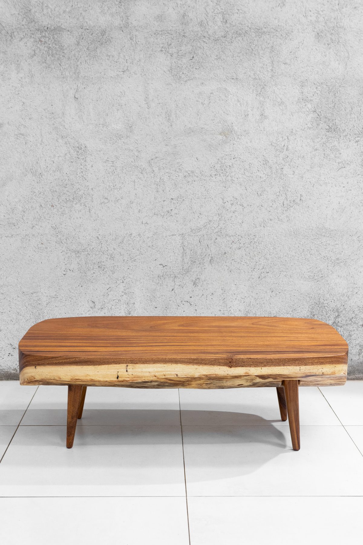 Sabana III Guanacaste coffee table seen straight on, honey-toned with a quiet live edge