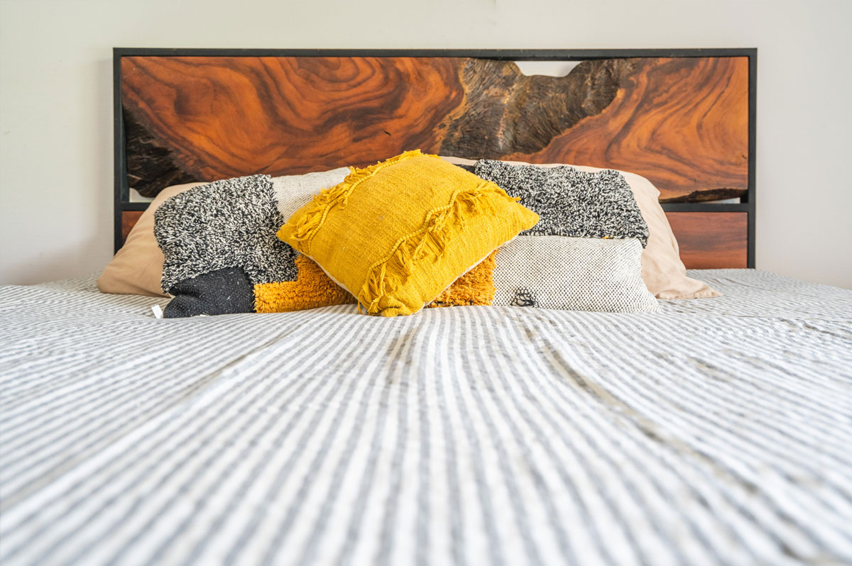 Detail of the Cama Refugio's Guanacaste headboard slab behind styled pillows