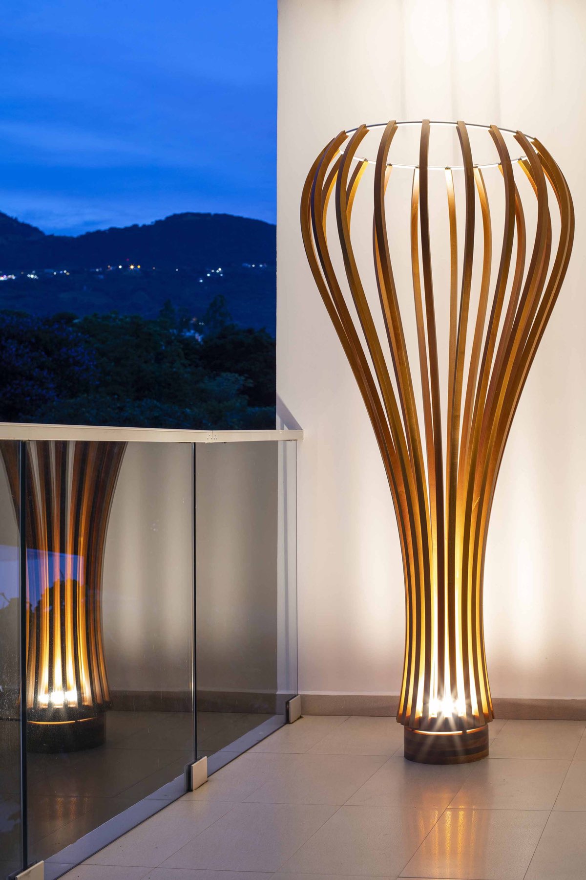 Glow of Grace cedar floor lamp lit at dusk, warm light through curved ribs, sculptural lighting Costa Rica