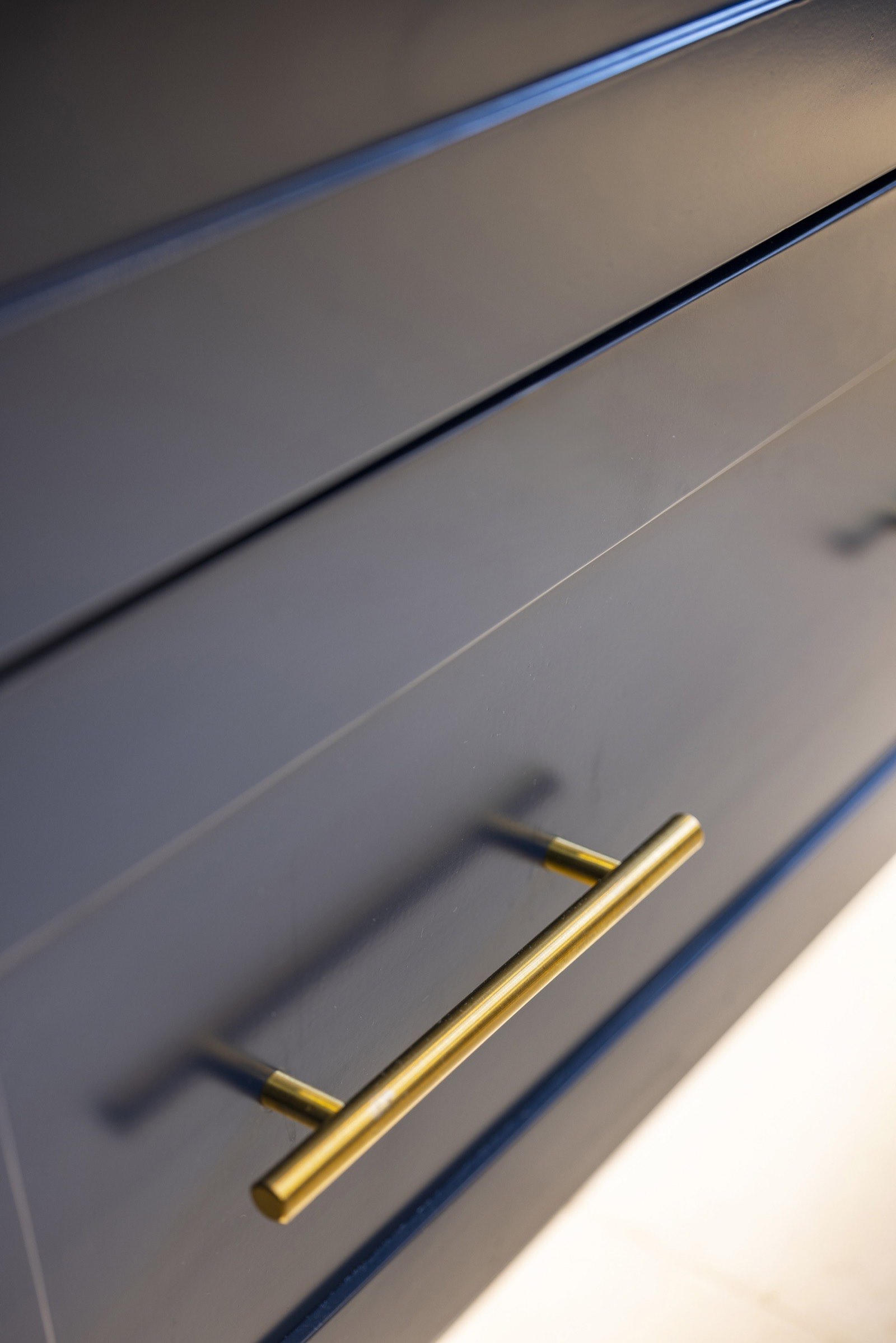 Brass bar pull on a navy shaker drawer front — hardware detail