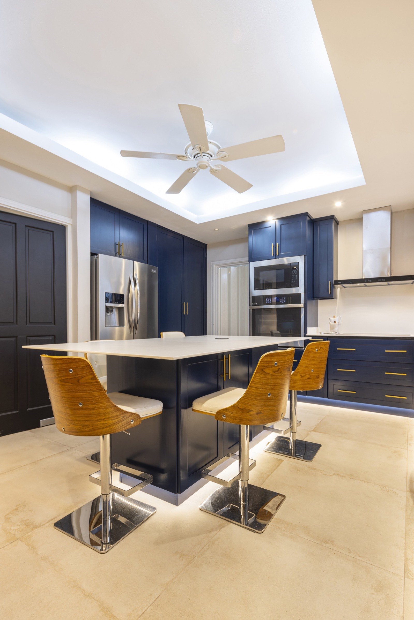 The full Jacamarca kitchen — navy cabinet run, island seating and vaulted ceiling