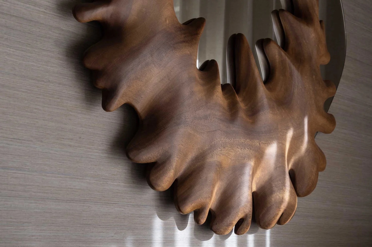 Detail of the Coral Mirror's hand-carved Guanacaste edge against a grasscloth wall