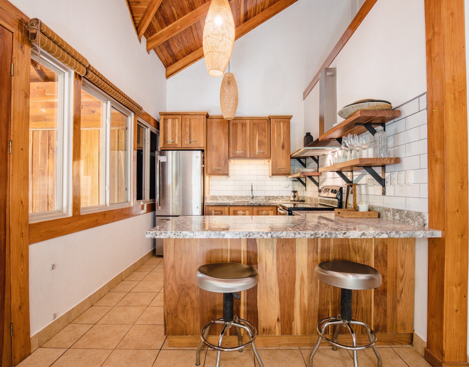The Playa Guiones 506 kitchen — Laurel cabinetry and peninsula seating under a vaulted wood ceiling