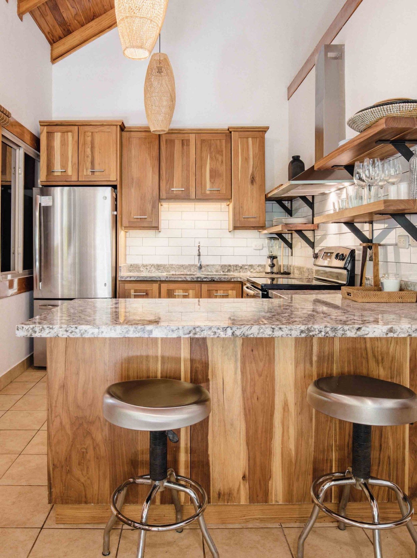 Playa Guiones 506 kitchen — solid Laurel cabinetry with granite counters, a peninsula and open shelving, seen straight on