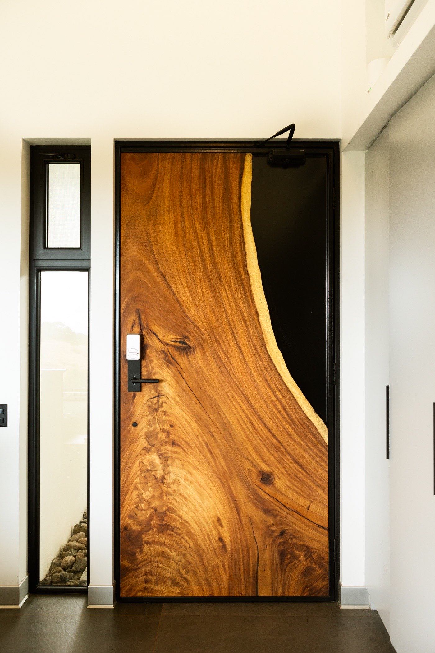 The Sarapiquí door from the entrance, its curved Guanacaste edge sweeping across the slab
