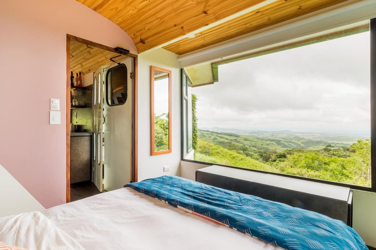 Bedroom inside a converted bus with a hand-built Guanacaste hardwood desk facing the jungle
